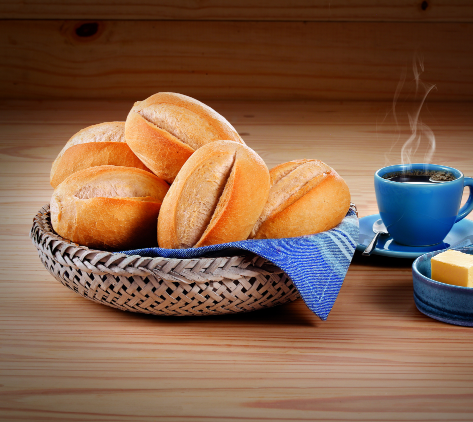 Pães sobre um cesto ao lado de uma xícara de café